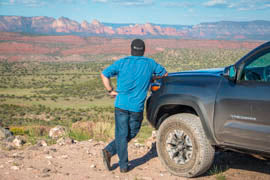 Andre Racine with his back to the camera, looking out towards a mountain vista